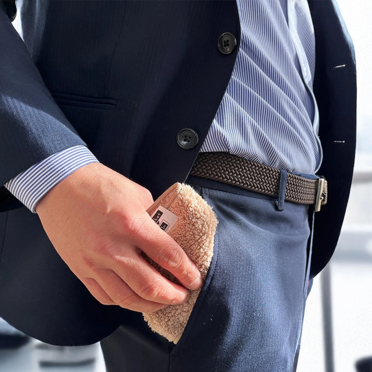 OBORO Pocket – vyras deda sulankstytą smėlinį rankšluostį į kelnių kišenę